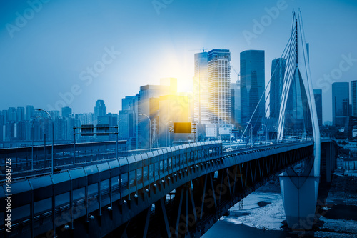 Long bridge across river with cityscape in background. © fanjianhua