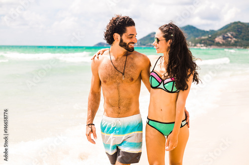 Arabic middle Asian man with a European white woman, a family fashion couple on a tropical vacation, having fun, laughing, having a good time, walking along the beach of the sea, the ocean. life style