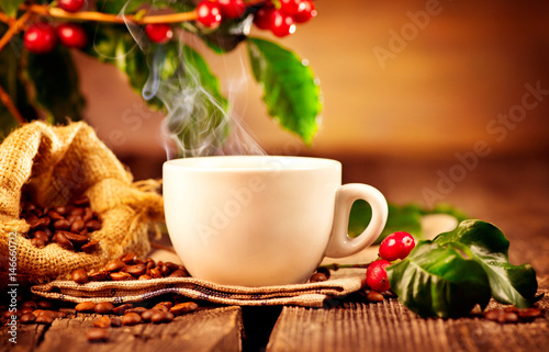 Coffee. Cup of hot steaming coffee closeup and real coffee beans over wooden background