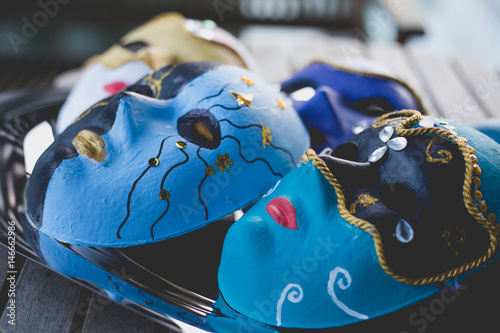 Closeup of beautiful masks made in the venetian style with acrylic paint and decoration, on the silver tray and wooden table