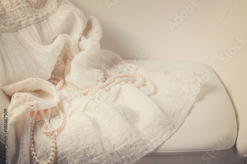 Female dress and jewellery on white chair still life, retro toned