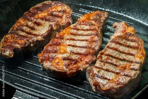 Raw Ribeye Steak with Herbs and Spices, frying on grill pan