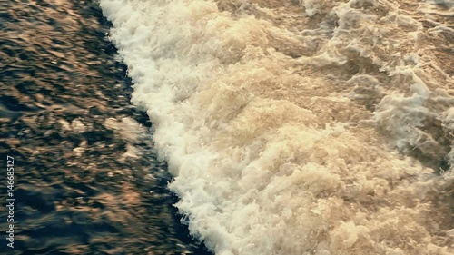 Amazing straight foamy wave from a sluice gateway on the Vltava river in Czech republic at an amazing sunset in the evening twilights of an early spring, being shot in slow motion photo