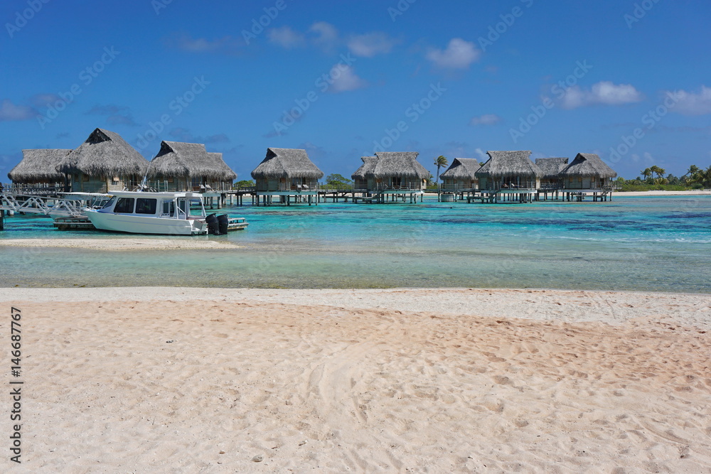 Tropical overwater bungalows in the lagoon seen from a sandy beach shore, atoll of Tikehau, Tuamotu, French Polynesia, south Pacific ocean