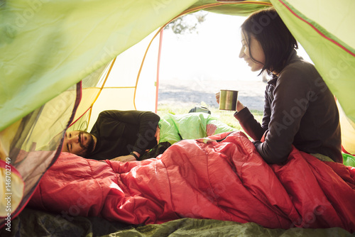 Couple traveling, spending time in tent, drinking coffee in the morning