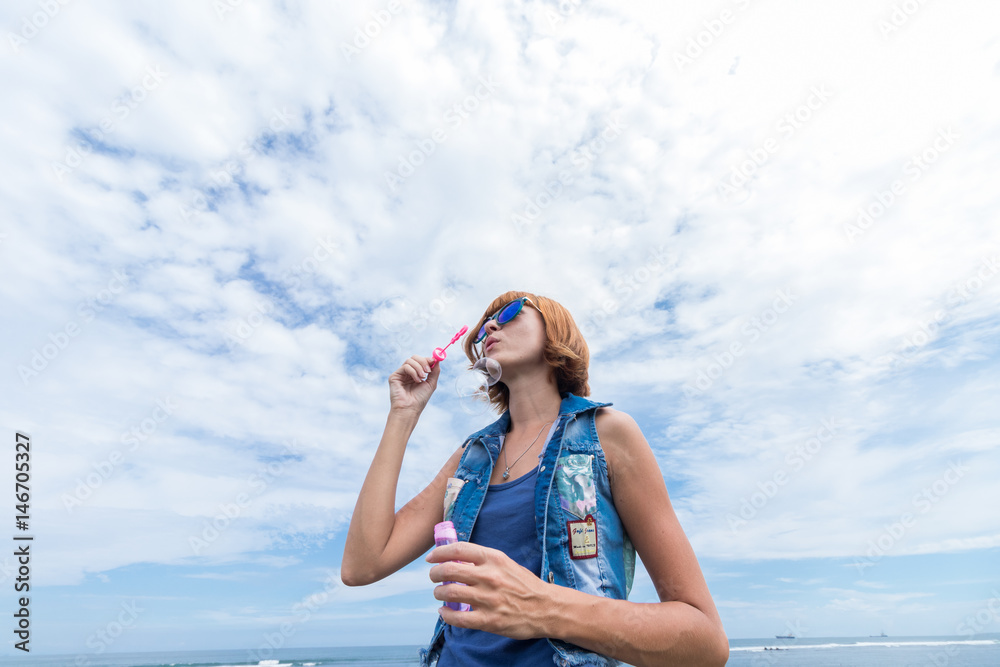 Beautiful young woman blowing bubble in outdoor, nature, near the ocean. Tropical magic island Bali, Indonesia. Beautiful young woman blowing bubble in outdoor, nature, near the ocean. Tropical magic island Bali, Indonesia.