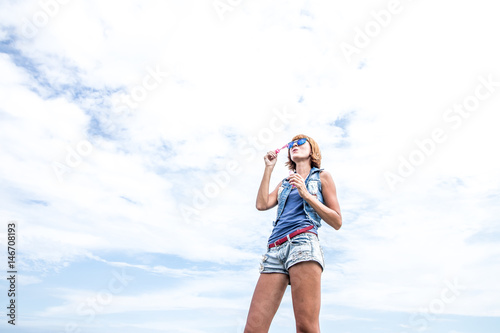 Beautiful young woman blowing bubble in outdoor, nature, near the ocean. Tropical magic island Bali, Indonesia.