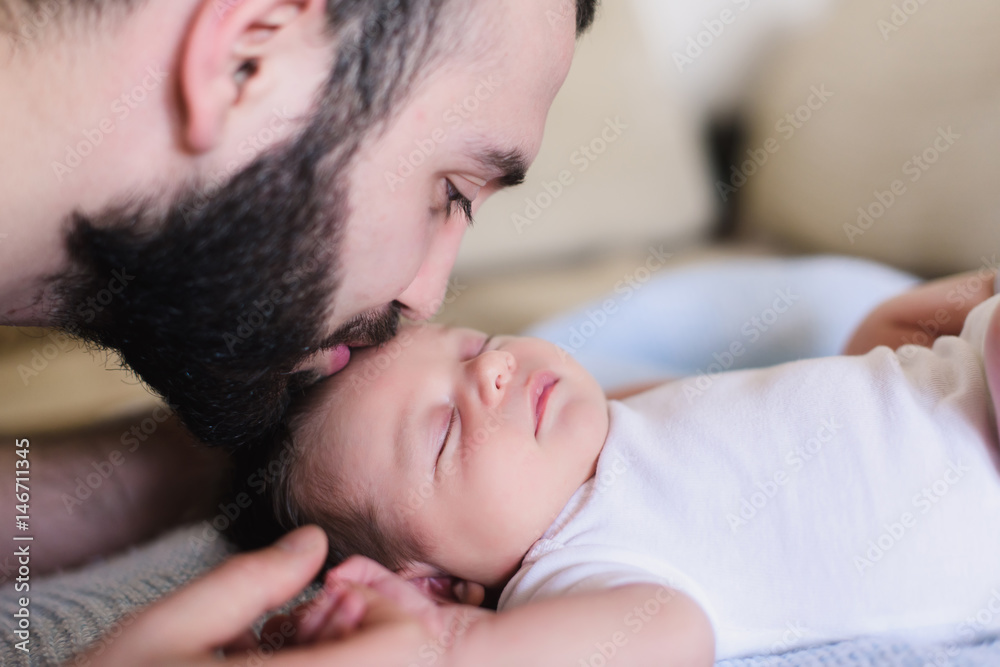 Young father kisses his newborn baby