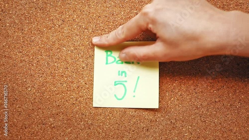 A hand sticking a memo note reading 'Back in 5'. photo