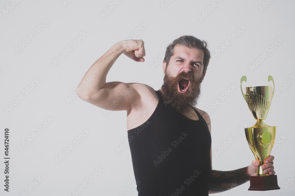 bearded happy man holds gold champion cup on grey background