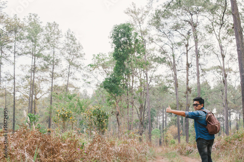 A man hitchhiking in the pine forest park, Thailand. © akeeris