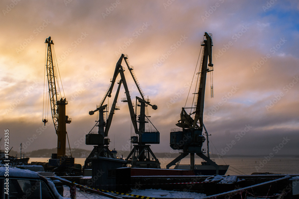 Port cranes at sunset sky background . Vyborg. Russia
