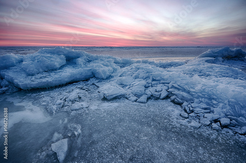 Abstract frozen winter sunrise seascape with ice and colored the sky.