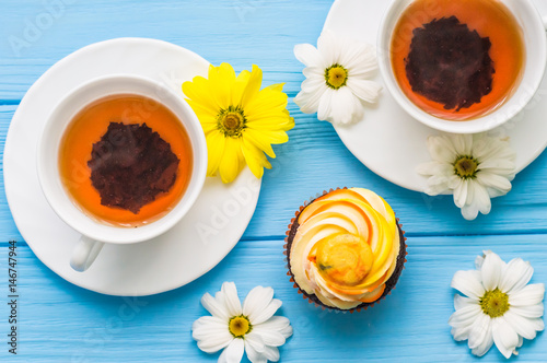 Still life with cup of tea and cake on the wooden background