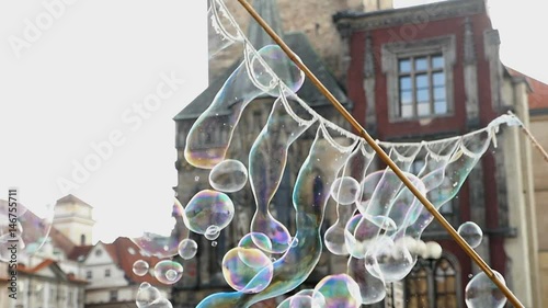 Dozens of soap bubbles made on Old Town Hall with its huge towers, historic multistoreyed  buildings, covered with red tile, impressive view,  in the daytime in spring, taken  as a slow motion shot photo