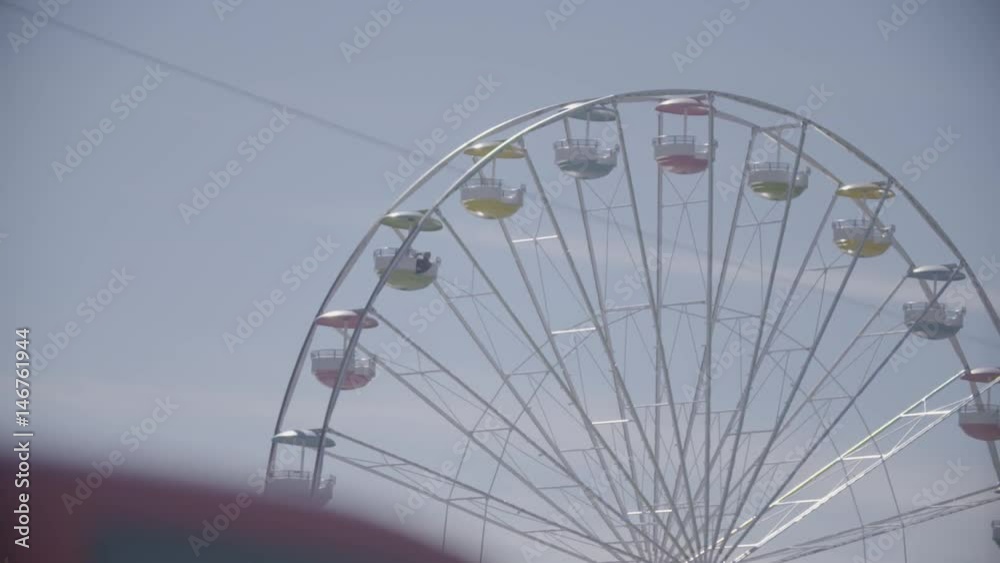Slow motion shot of observation wheel and cleer blue sky in amusement park. Entertainment industry concept. Leisure activities, sunny summer day. Slow motion shot of observation wheel and cleer blue sky in amusement park. Entertainment industry concept. Leisure activities, sunny summer day.