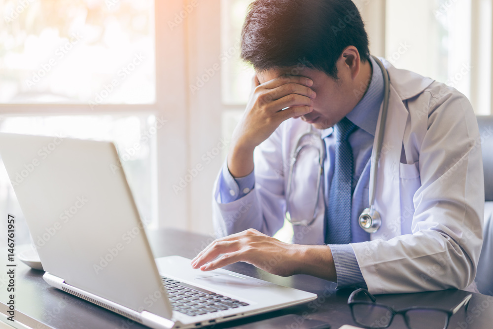 Portrait of a young handsome doctor using his laptop computer with serious Portrait of a young handsome doctor using his laptop computer with serious