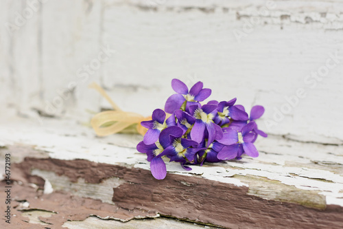 Small bouquet of violets on a wooden background 