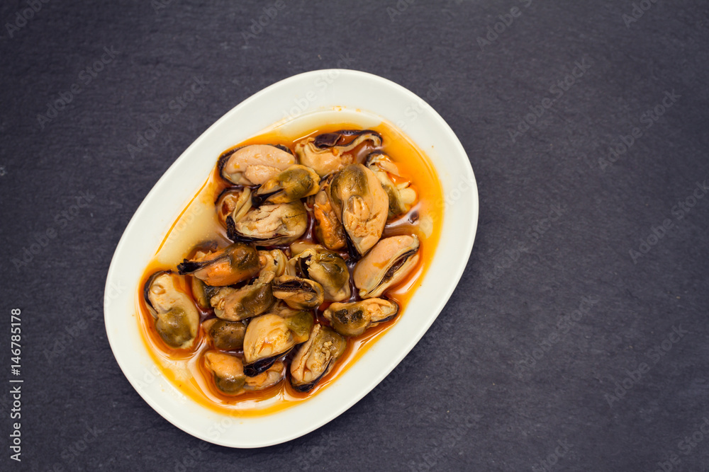 mussels in sauce on white dish on black wooden background mussels in sauce on white dish on black wooden background