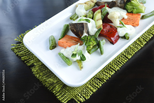 Grilled vegetables on a white plate, dark background