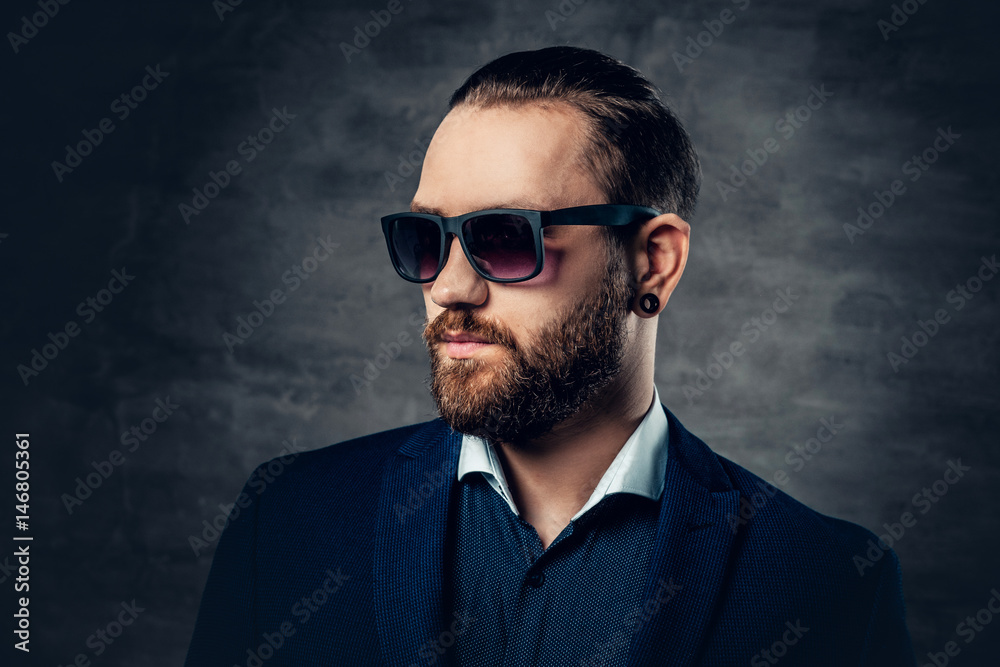 Studio portrait of bearded male in sunglasses and piercing in a nose.