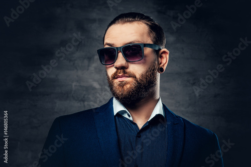 Studio portrait of bearded male in sunglasses and piercing in a nose.