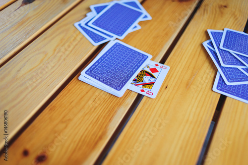 Deck of playing cards on a wooden table pile with an open trump card of a diamond lady.