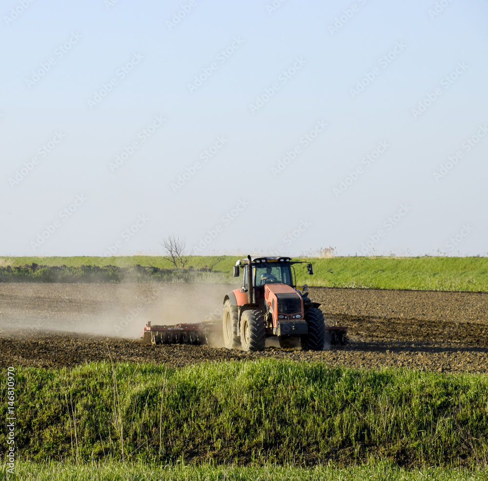 Fototapeta premium A tractor with a plow lays the soil. Soil cultivation on the fie