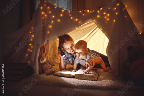 mother and baby son with a book and a flashlight before going to bed