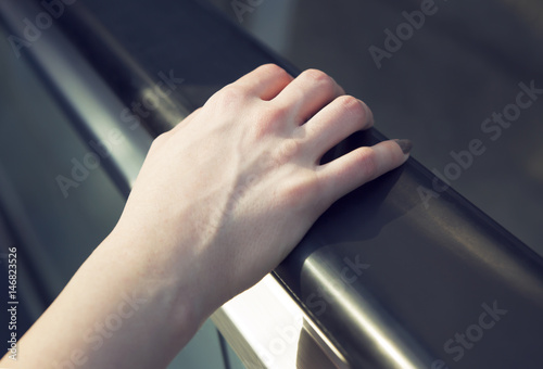 A female hand holds an escalator railing 
