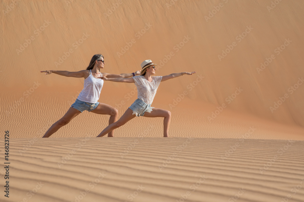 Two women doing yoga in the desert.