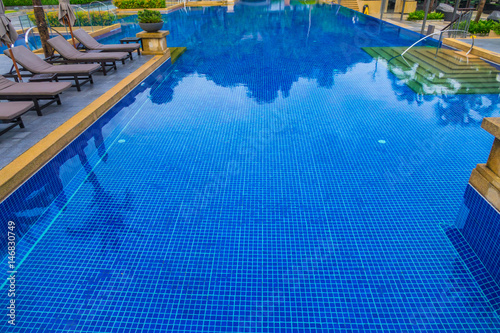 Swimming pool with relaxing seats near the sea .