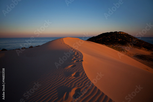 footprints on the sand dunes on a sunset in a desert