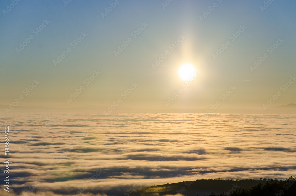 sunset view over colorful valley full of dense mist, fog colored with hot sun rays. orange Light on sunrise