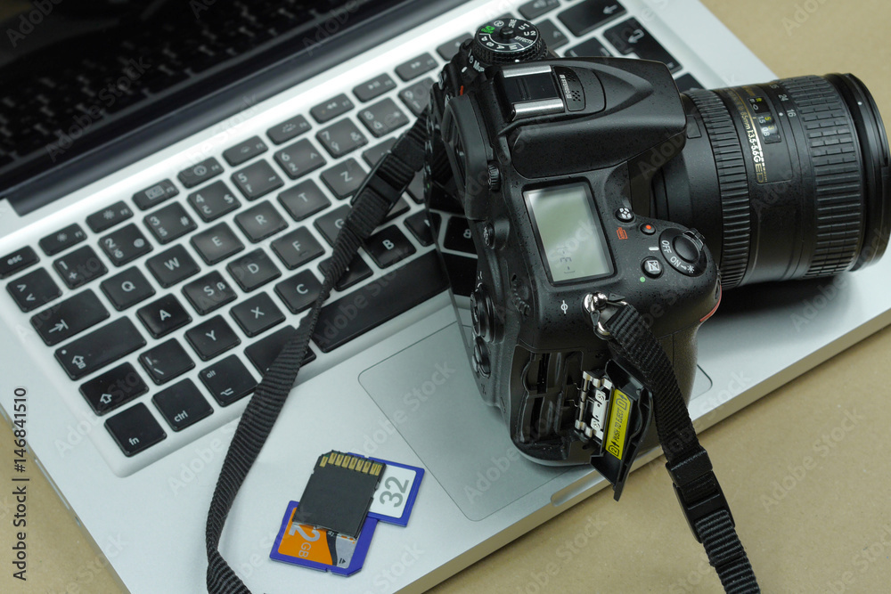 Digital DSLR Camera with laptop in the background.