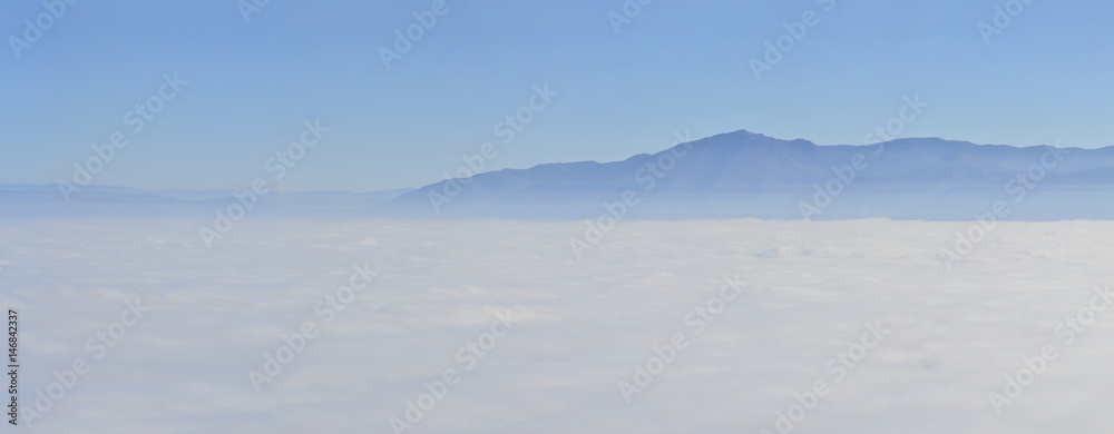 mountain landscape with waves of fog, aerial pov
