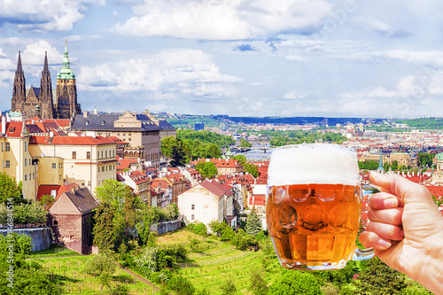 Photography Hand with a mug of beer on the background of the panorama of Prague