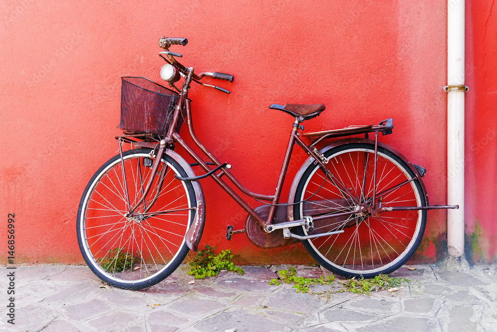 Old bicycle on a red wall background