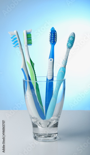 Toothbrushes in glass on color background