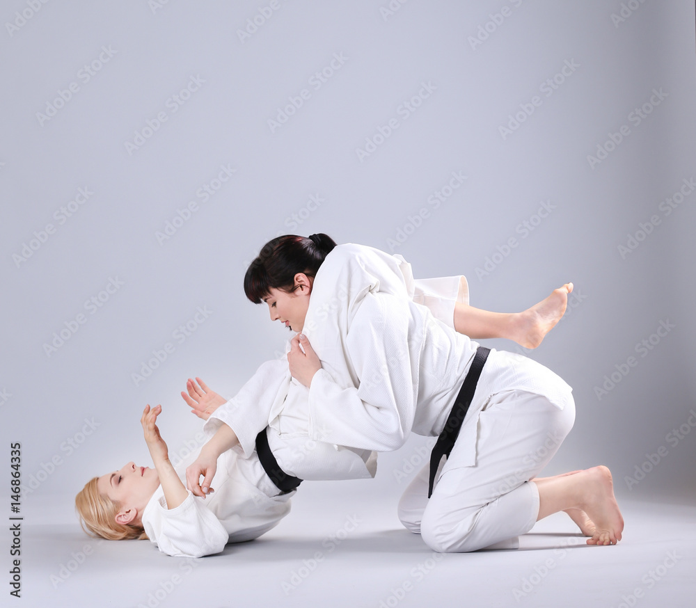 Young sporty women practicing martial arts on light background Young sporty women practicing martial arts on light background