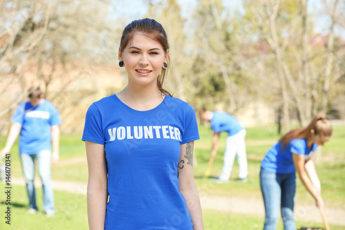 Beautiful young volunteer with team outdoors