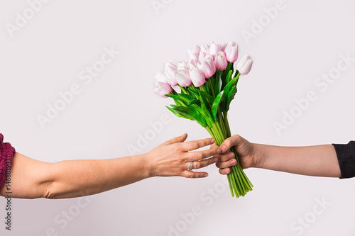 Manos cogiendo un ramo de tulipanes rosas.