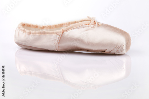 Pretty pink satin ballerina dancing shoe on a white surface. Pointe shoe isolated on white background.