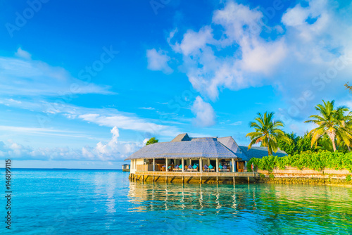 Beautiful water villas in tropical Maldives island at the sunrise time .