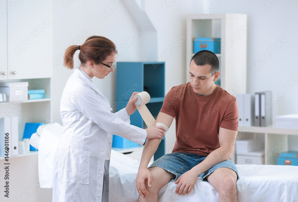 Obraz premium Orthopedist applying bandage onto patient's arm in clinic