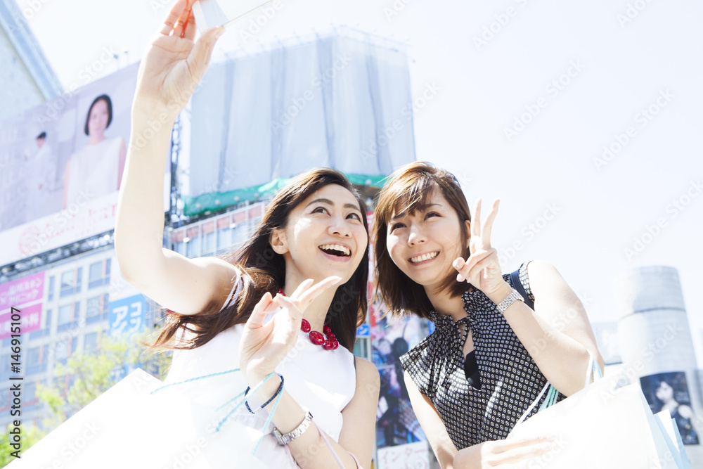 Naklejka premium Two young ladies are shooting at Shibuya