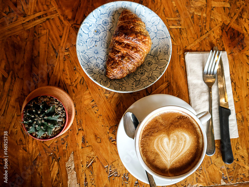 morning Croissant and latte art coffee with work and relax time on wooden table coffee shop