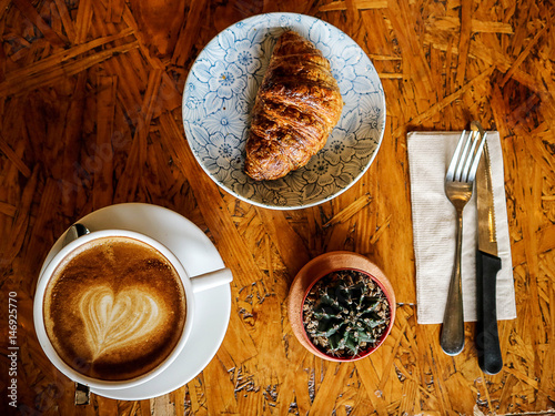 morning Croissant and latte art coffee with work and relax time on wooden table coffee shop