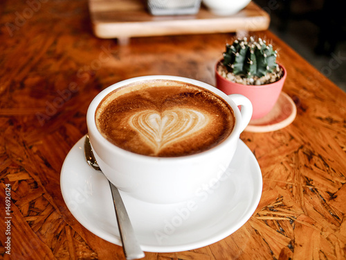 morning latte art coffee cup and cactus with work and relax time on wooden table coffee shop  