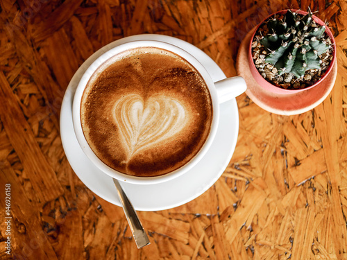 morning latte art coffee cup and cactus with work and relax time on wooden table coffee shop  